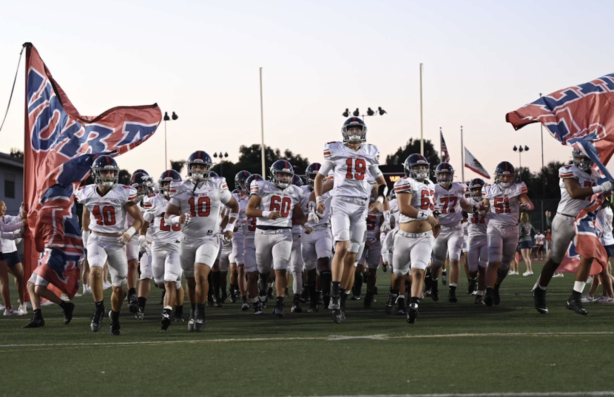 The team running onto the field as the Mustangs cheer them on.